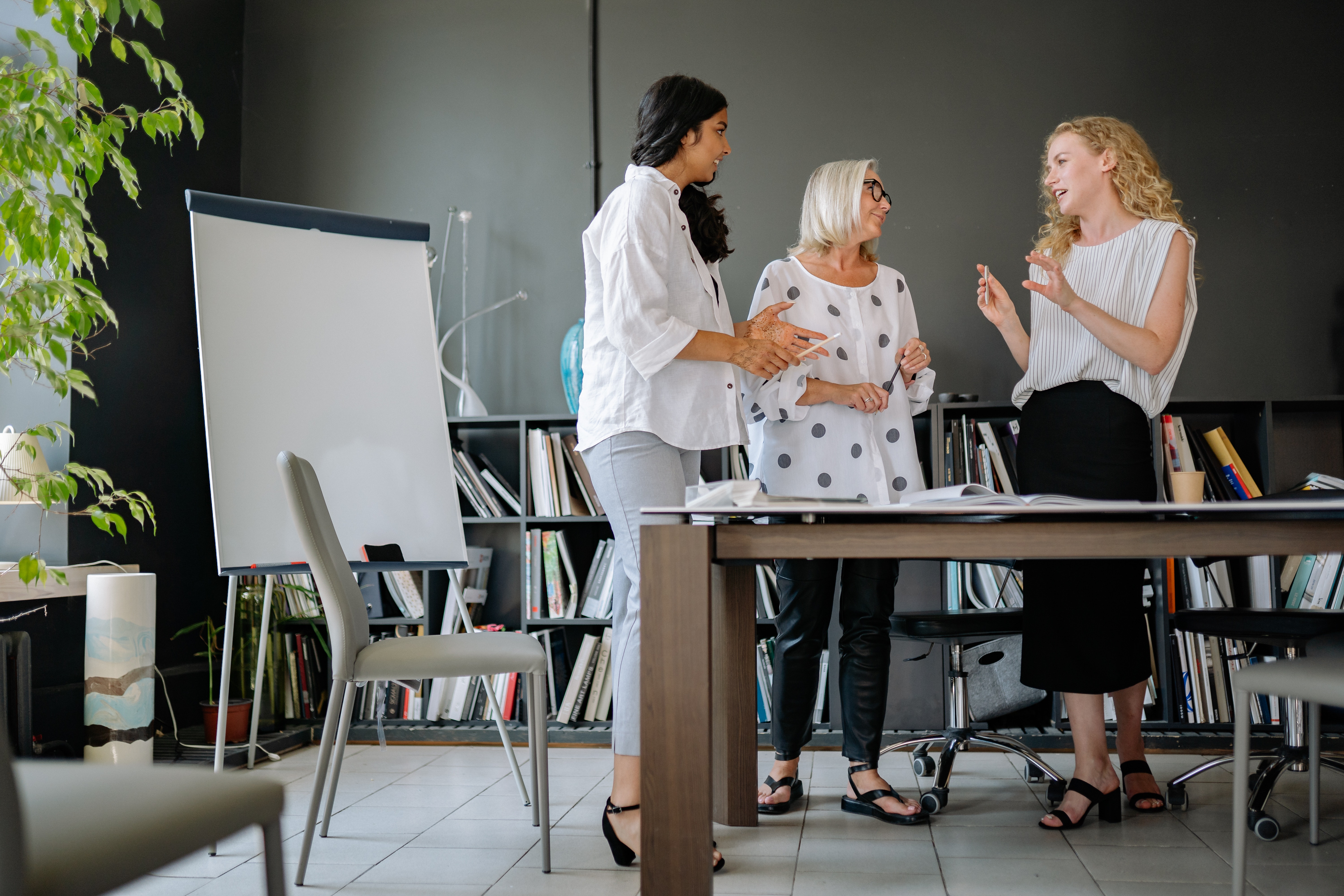 3 women talking at conference table (photo by Photo by Yan Krukov)