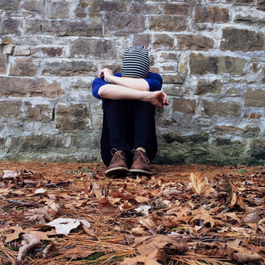 person with head down against wall